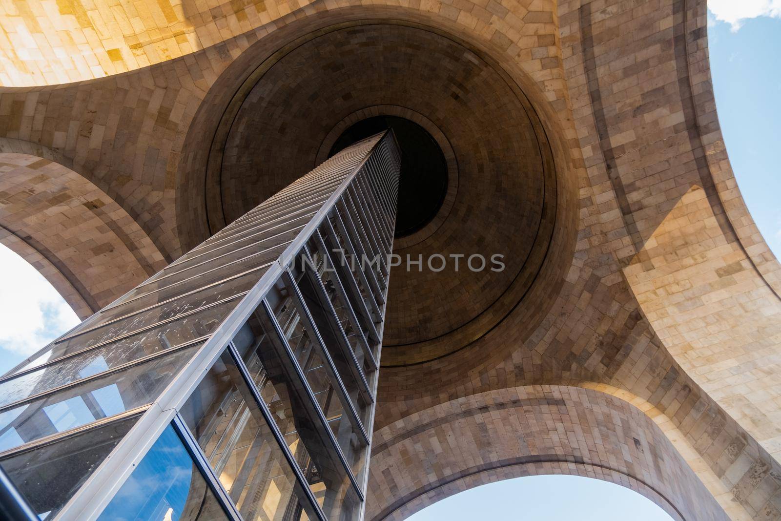 Low angle view of the interior and glass elevator of the Monument to the Revolution. Majestic triumphal arch in Mexico City with slightly cloudy sky as background. Mexican landmarks