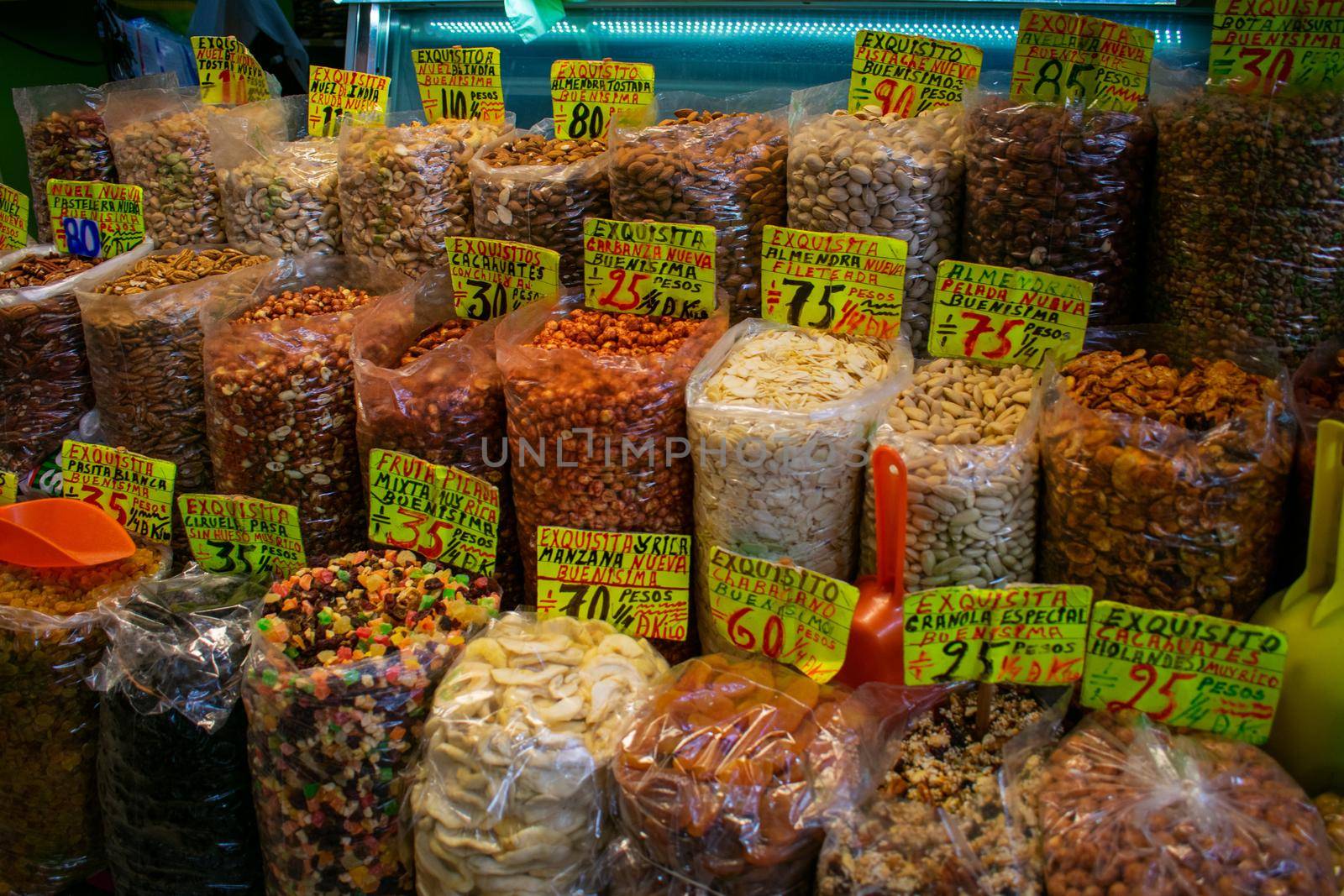 Fresh nuts and dry fruit in plastic bags for sale. Huge variety of nuts displayed with description and price tags in Mexican market. Healthy ingredients