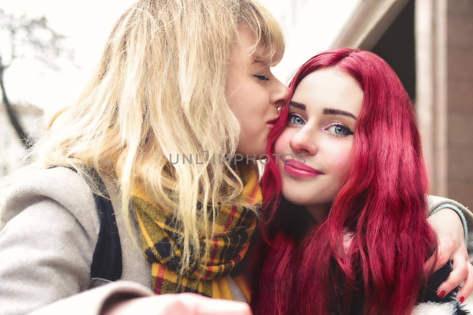 LGBT blonde Lesbian girl kissing forehead of her loving girlfriend with pink hair, gentle attitude, first love. lesbian couple. by Nickstock