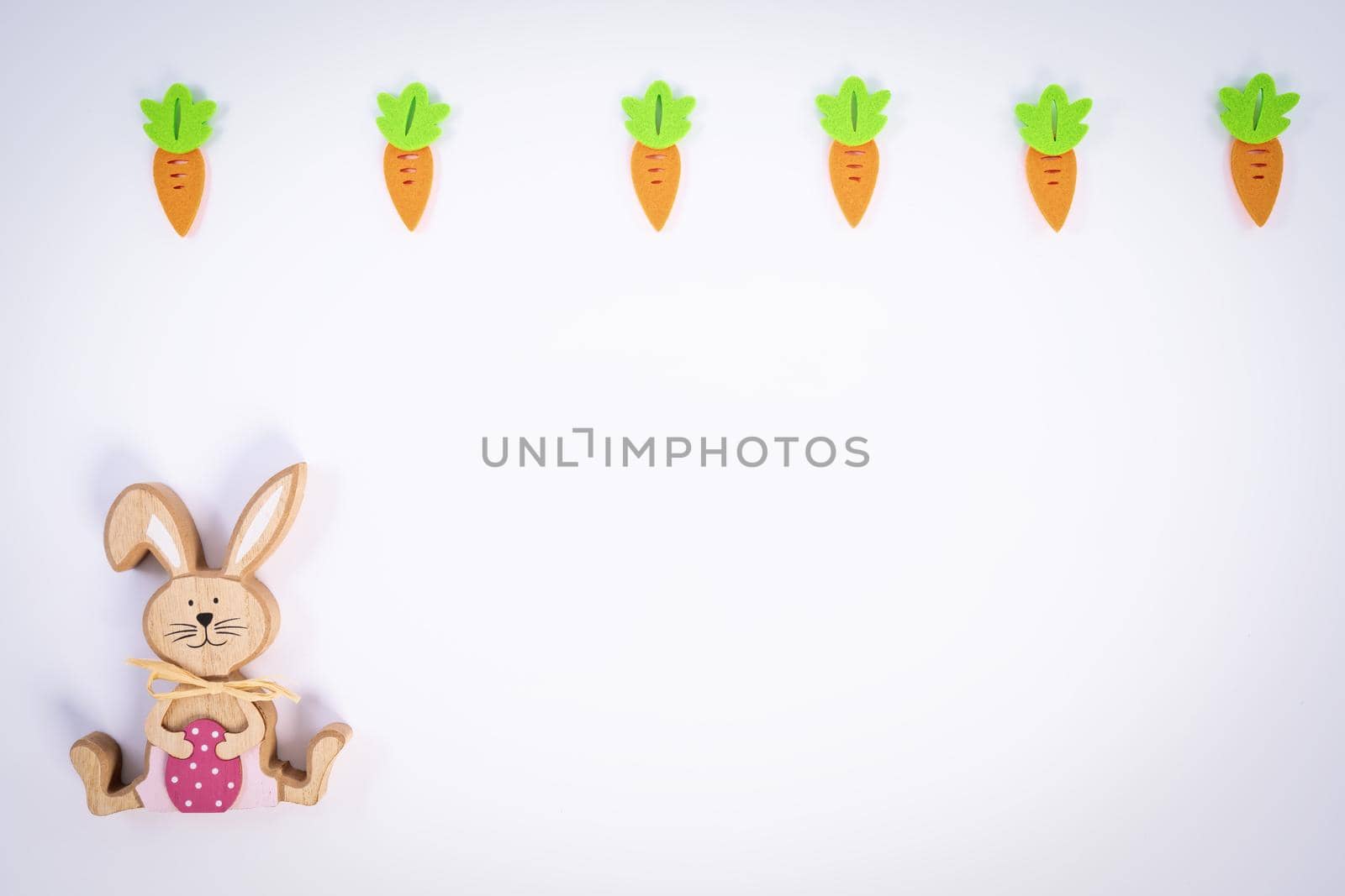 Easter pattern made with carrots and a cute Easter bunny on white background. Creative minimal holiday flat lay concept. Spring holidays concept. Top view. Copy space.