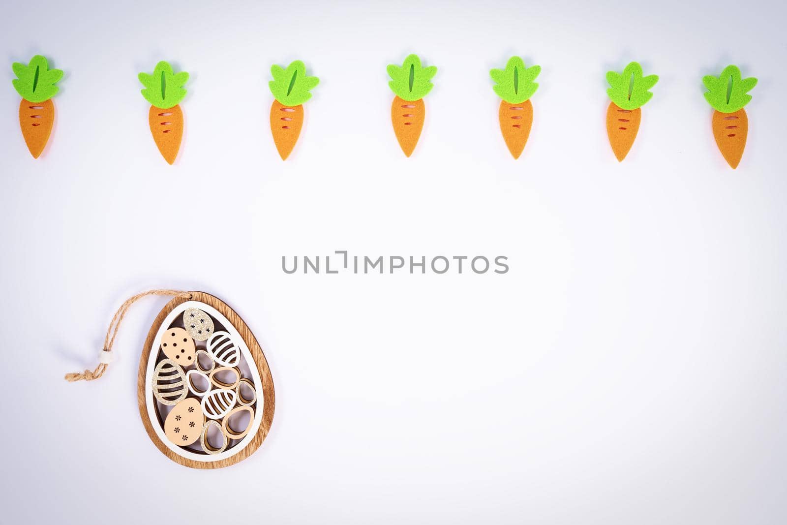 Easter pattern made with carrots and a cute Easter egg decoration on white background. Creative minimal holiday flat lay concept. Spring holidays concept. Top view. Copy space.