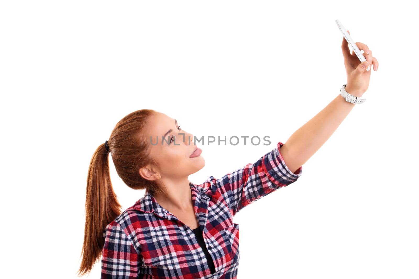 Beautiful smiling casual young girl taking a selfie with her tongue out, isolated on a white background. Social media and selfie concept.