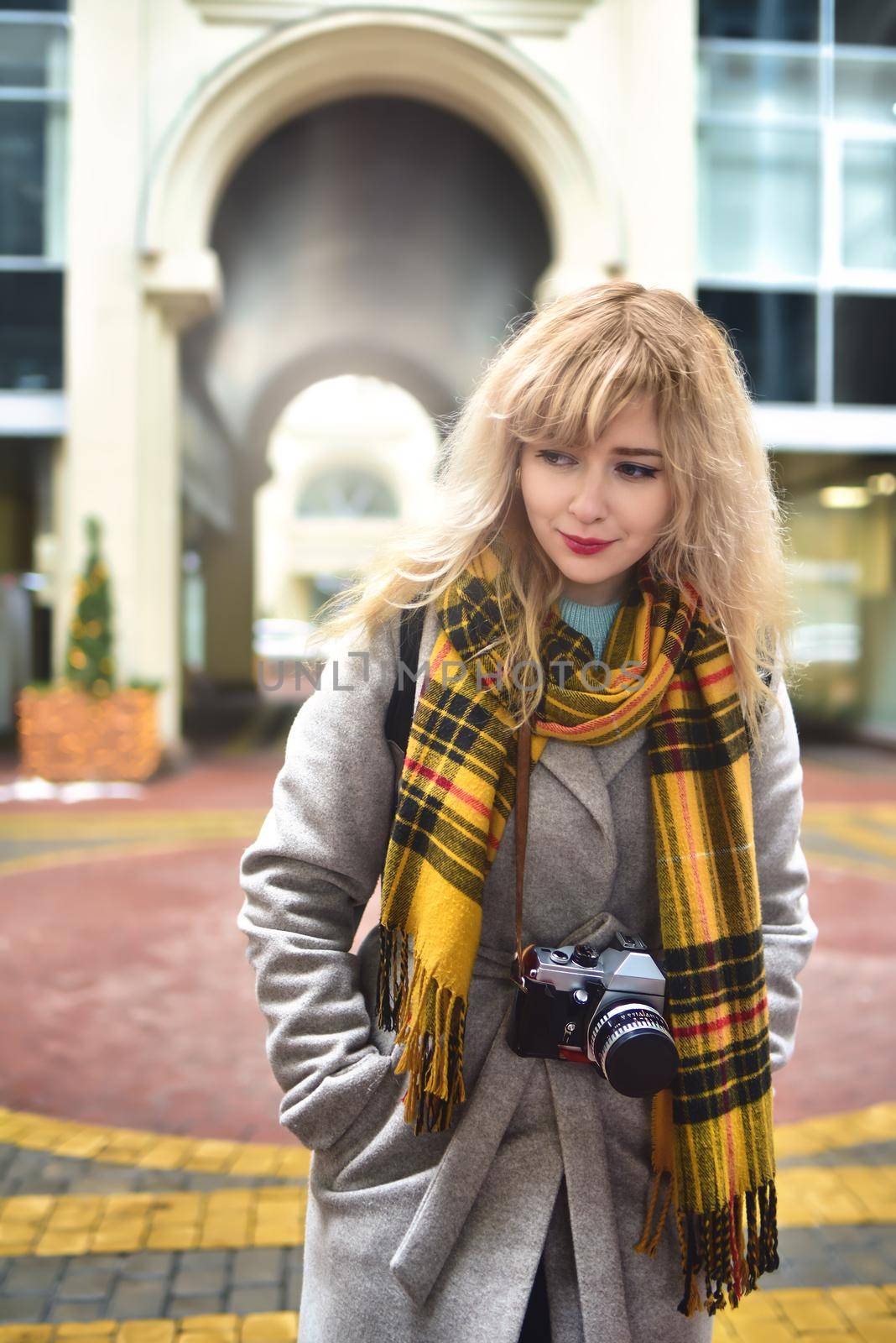 Blonde pretty photographer woman with retro camera in her hands while taking shots at urban old architecture. Discover new places. by Nickstock