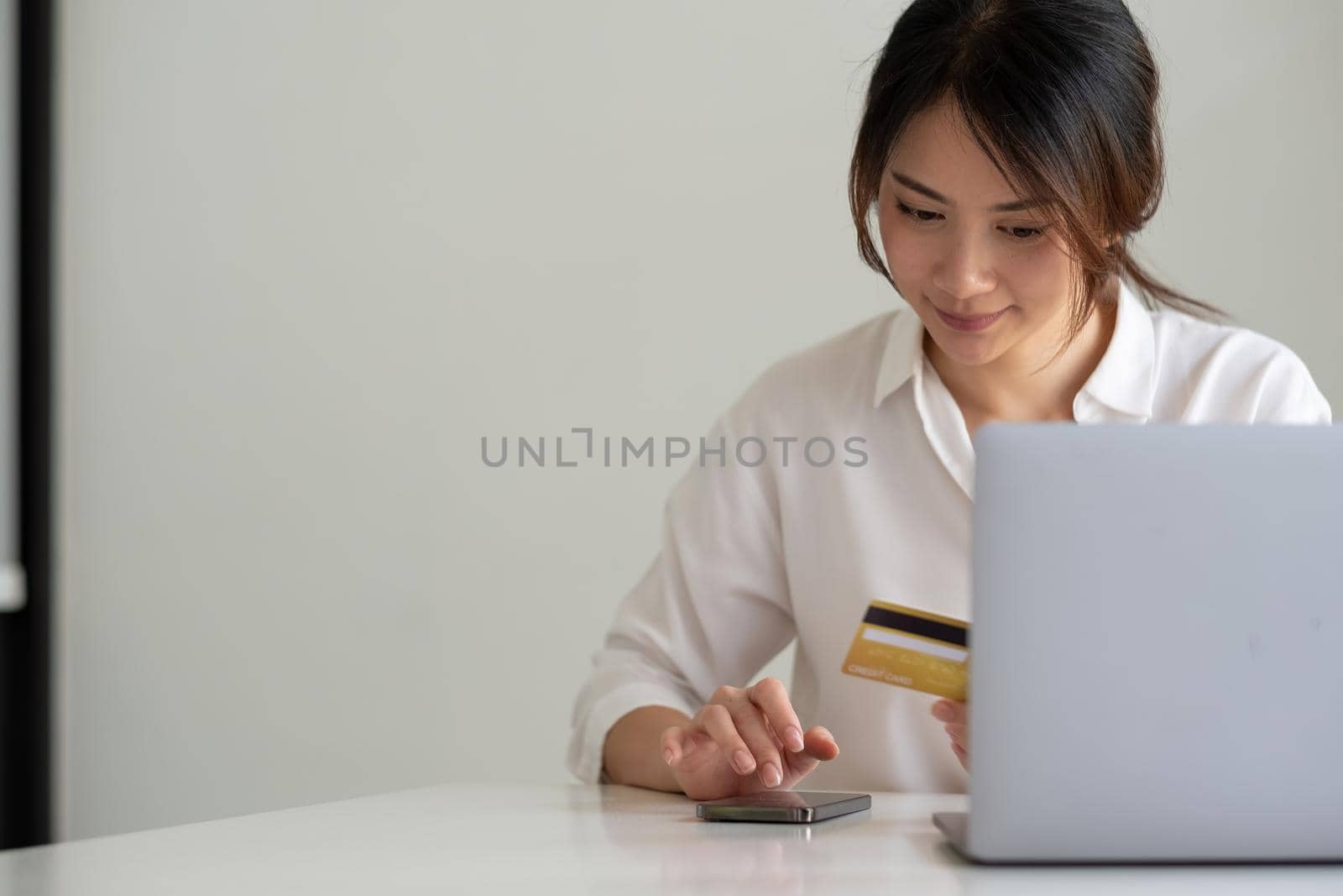 Happy woman using smart phone and laptop computer and credit card for shopping online at home by nateemee