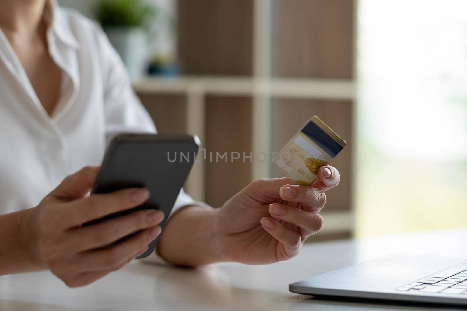 Close up woman using smartphone and credit card for shopping online at home. by nateemee