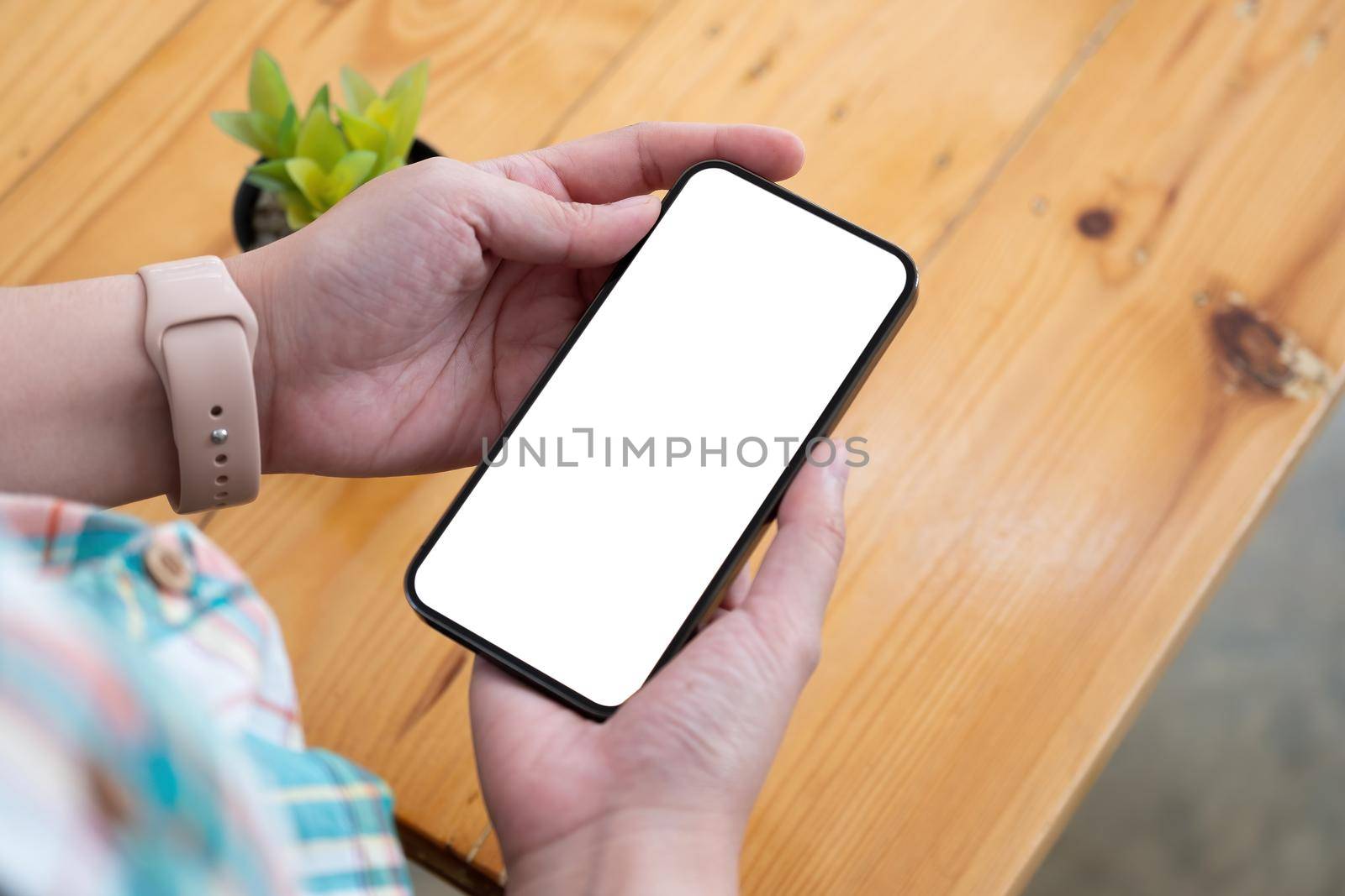 Top view Woman sitting and holding blank screen mock up mobile phone, by nateemee