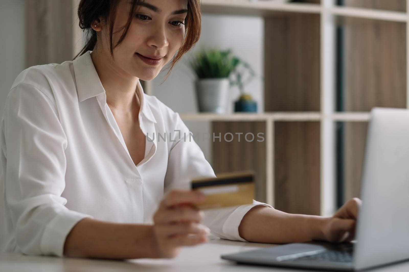 Happy woman using laptop computer and credit card for shopping online at home. by nateemee