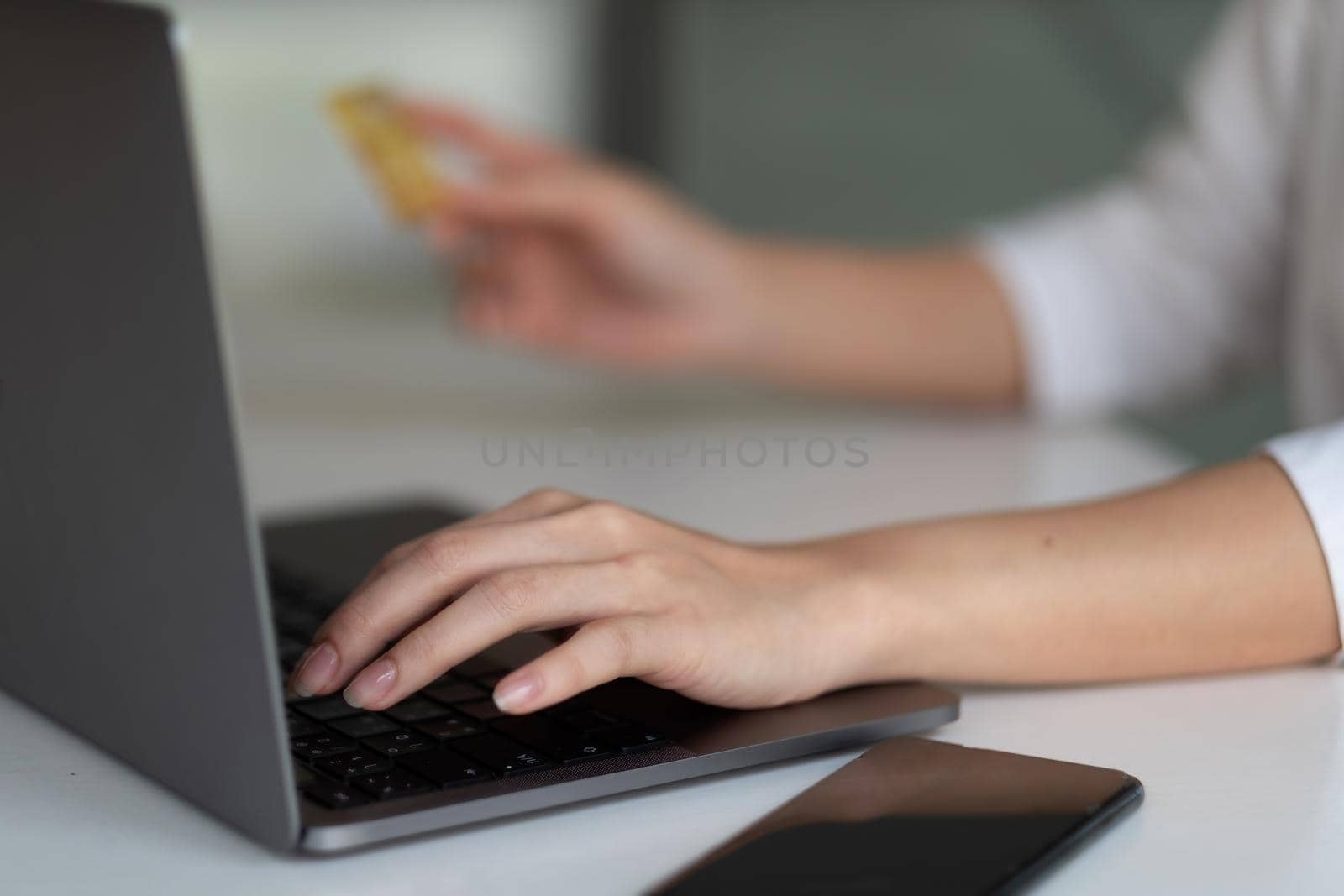 Close up hand of woman using laptop computer and credit card for shopping online at home. by nateemee