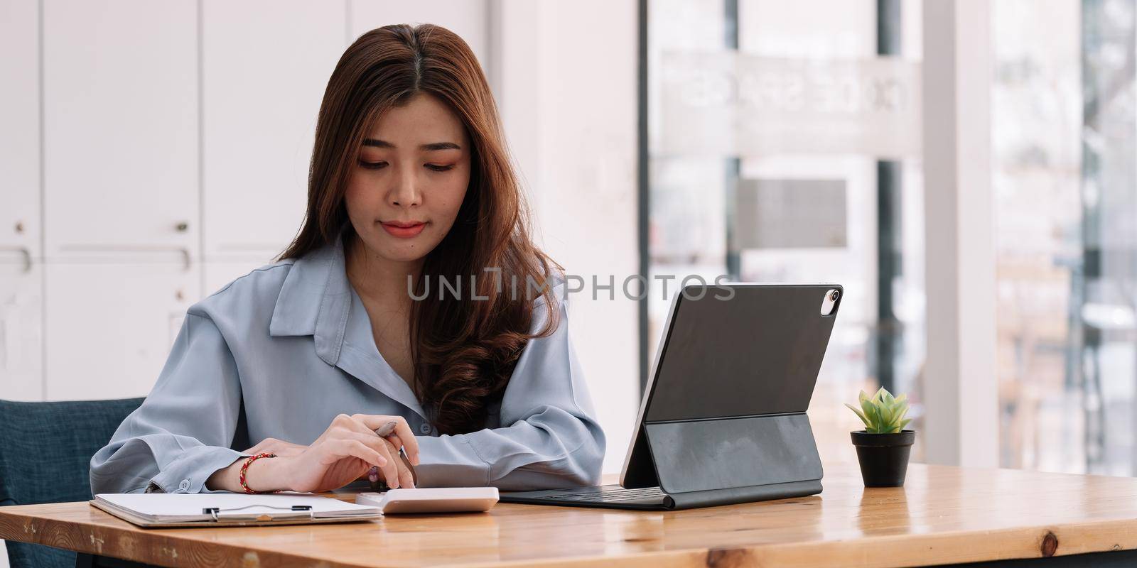 Business accounting concept, Businesswoman using calculator with computer laptop, budget tax and loan paper at home.