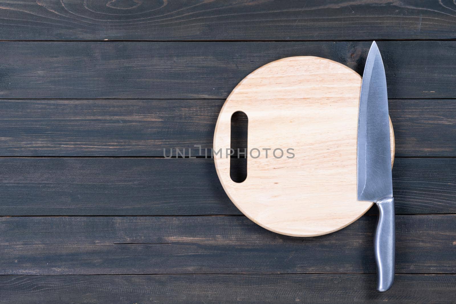 Kitchen knife on wooden round cutting board close up by stoonn