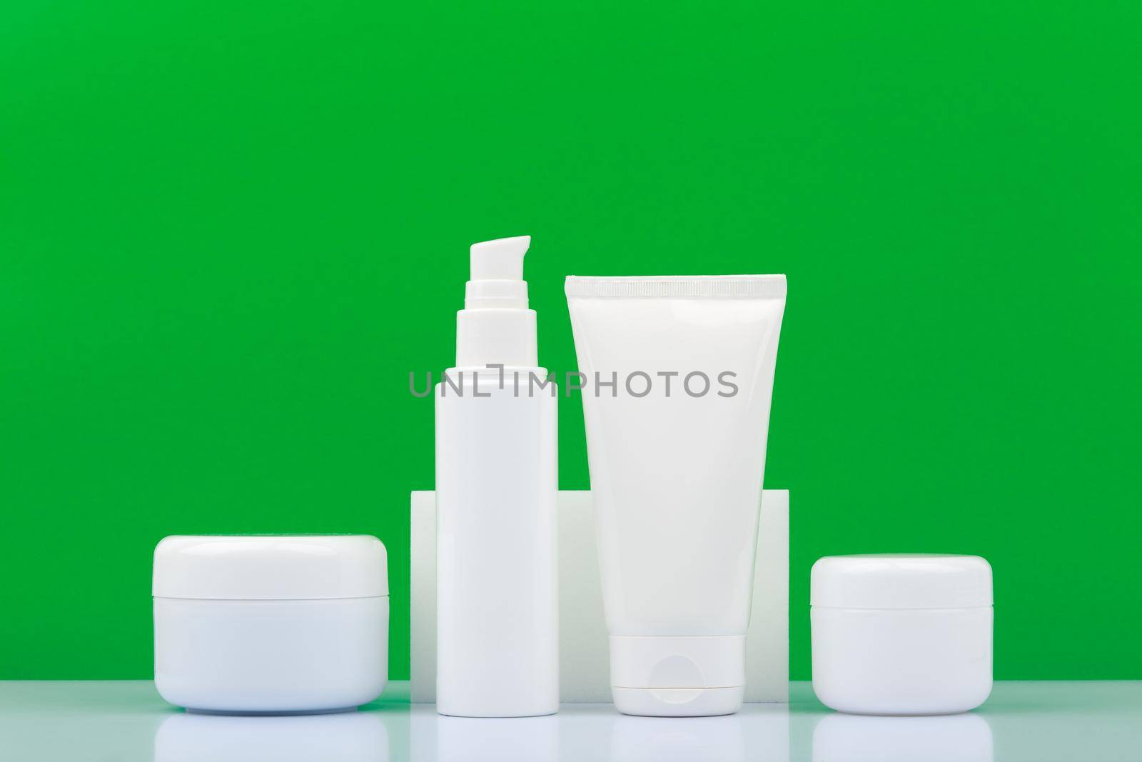 Set of cosmetic products for daily skin care on white table against green background. Concept of organic cosmetics with natural ingredients and oils. Beauty products with aloe vera or green tea 