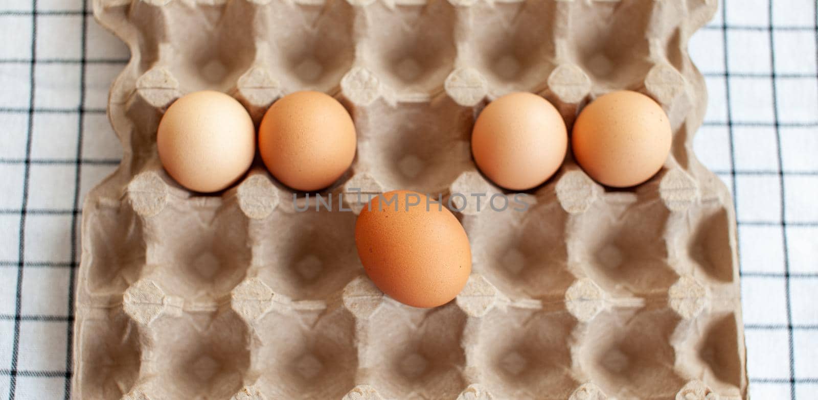 Several brown eggs lie in a row in a large cardboard bag, a chicken egg as a valuable nutritious product, a tray for carrying and storing fragile eggs