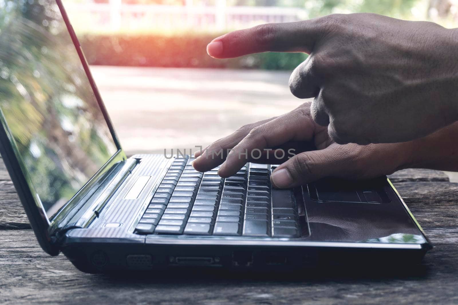 Hand Person working pointing to screen and using on a laptop computer for freelance with input keyboard for online blogger job to black computer on a wooden table at home.