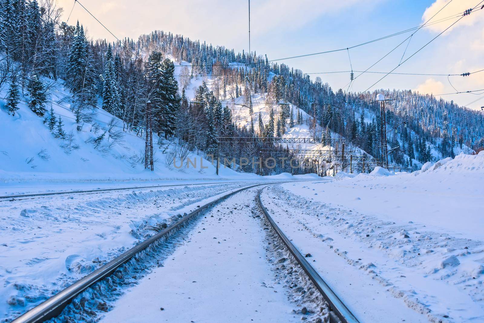 Snow-covered railway passing in the shade of beautiful winter mountains