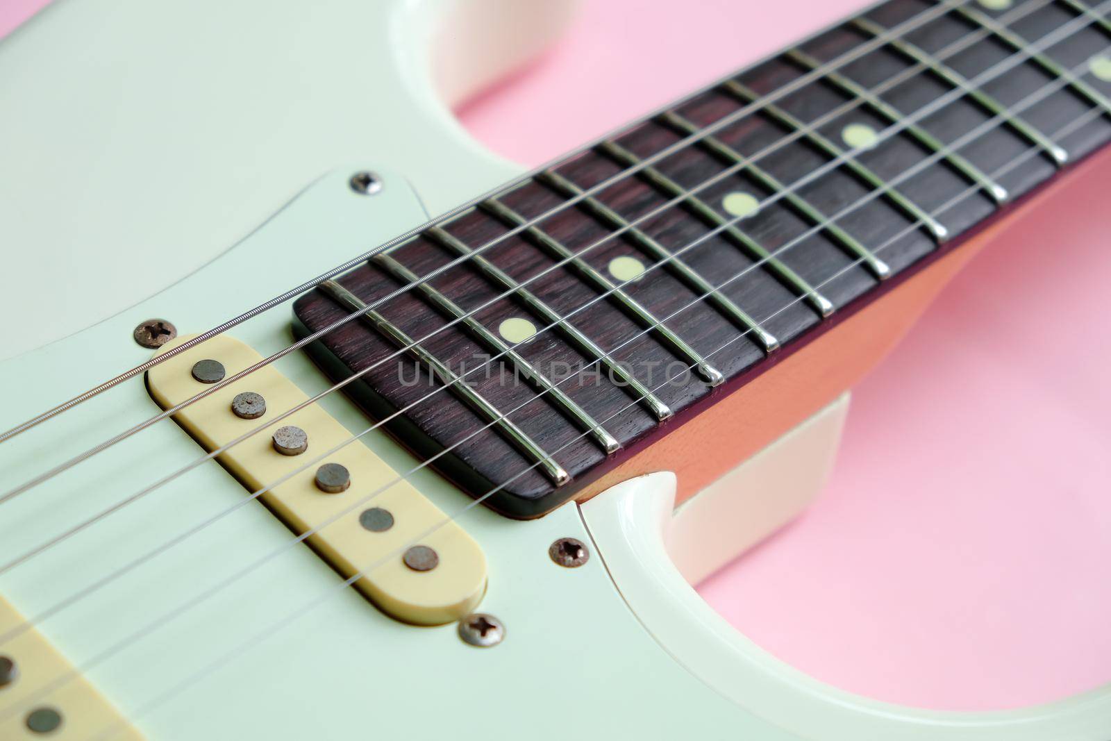 Detail of White Electric Guitar on a pink background.