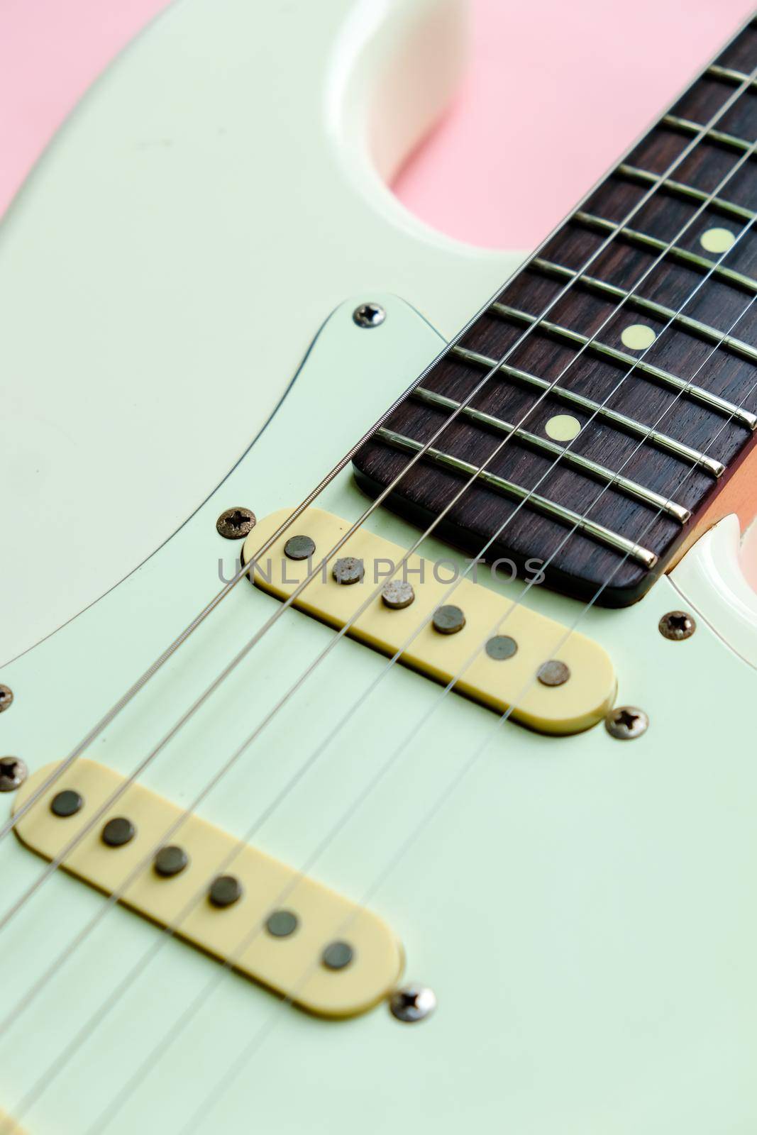 Detail of White Electric Guitar on a pink background.