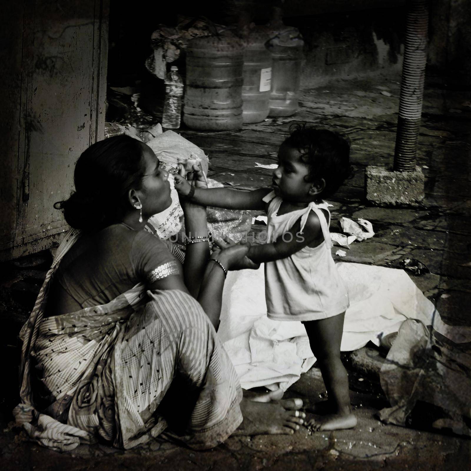 MUMBAI, INDIA - Feb 13, 2021: Daughter giving food to her mother on street-homeless by tabishere