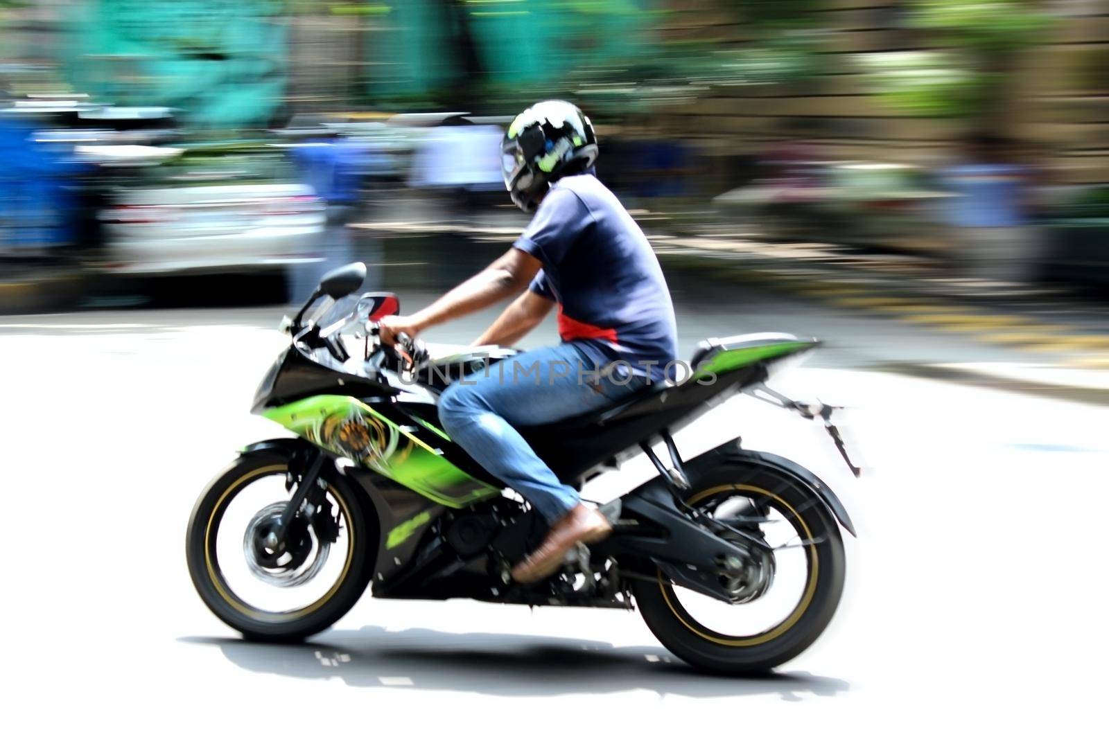 Motorcycle driver riding on road landscape with blurred motion effect of surrounding background. by tabishere