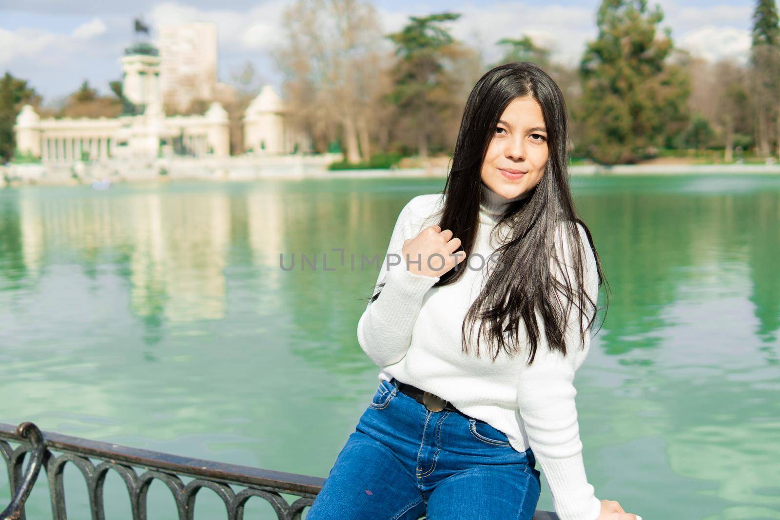 Young girl in blue jeans and white sweater with lake background by xavier_photo