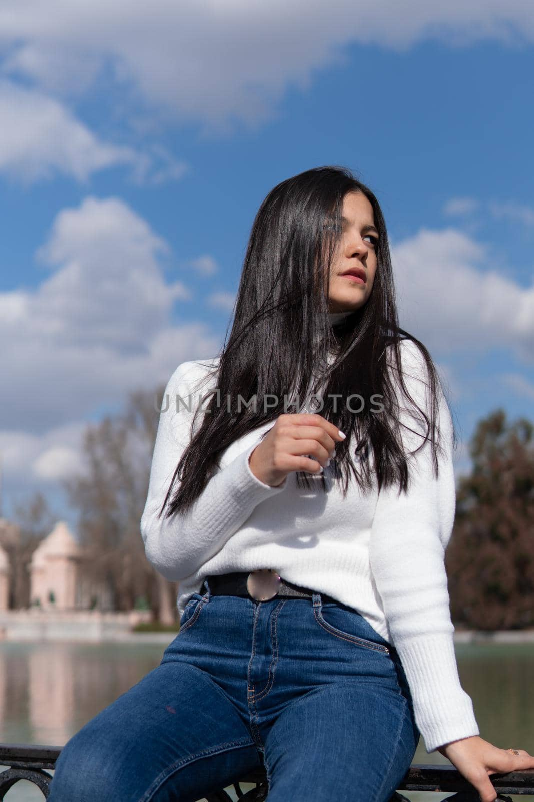 Young girl in blue jeans and white sweater with blue sky in the background by xavier_photo