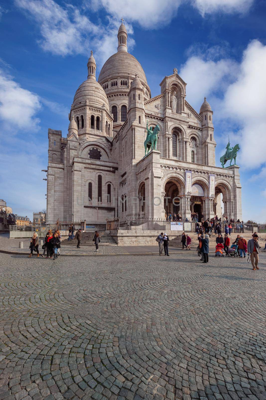 Paris - April 6, 2013: Tourists near the Basilica of the Sacred Heart of Paris (Sacre-Coeur). It is a the highest point in the city and popular landmark, and the second-most visited monument in Paris.