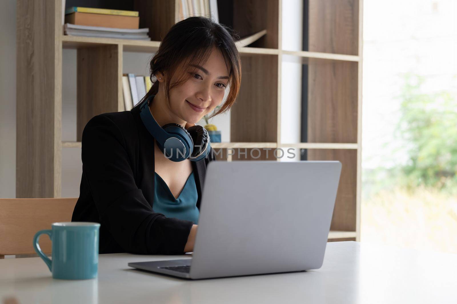 Portrait of asian woman studying online with laptop computer while sitting at the table and notebook at home.