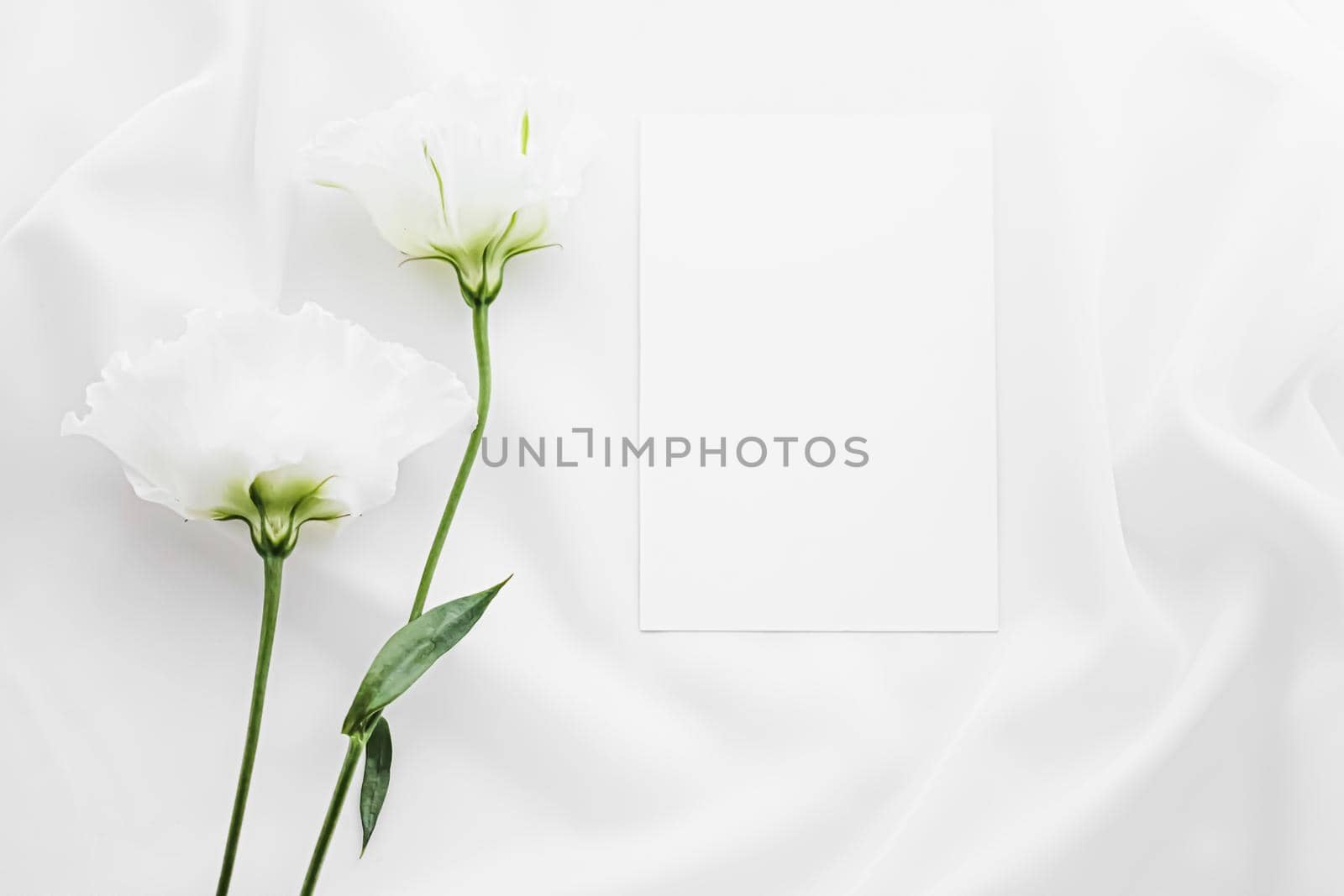 Wedding invitation and white rose flowers on silk fabric as bridal flatlay background, blank paper greeting card and holiday branding, flat lay design by Anneleven