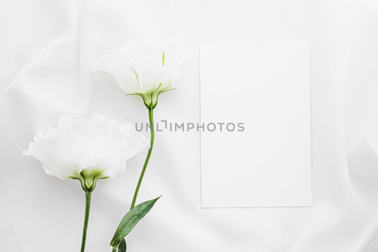 Wedding invitation and white rose flowers on silk fabric as bridal flatlay background, blank paper greeting card and holiday branding, flat lay design by Anneleven