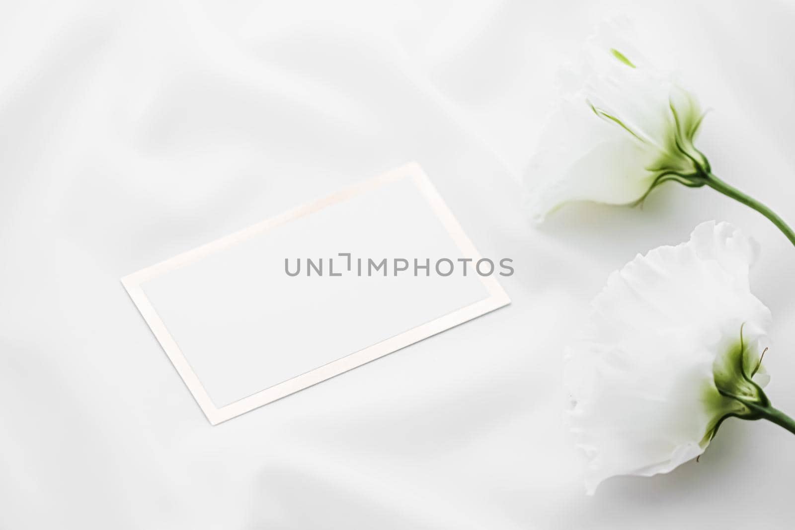 Wedding invitation or gift card and white rose flowers on silk fabric as bridal flatlay background, blank paper and holiday branding, flat lay design by Anneleven