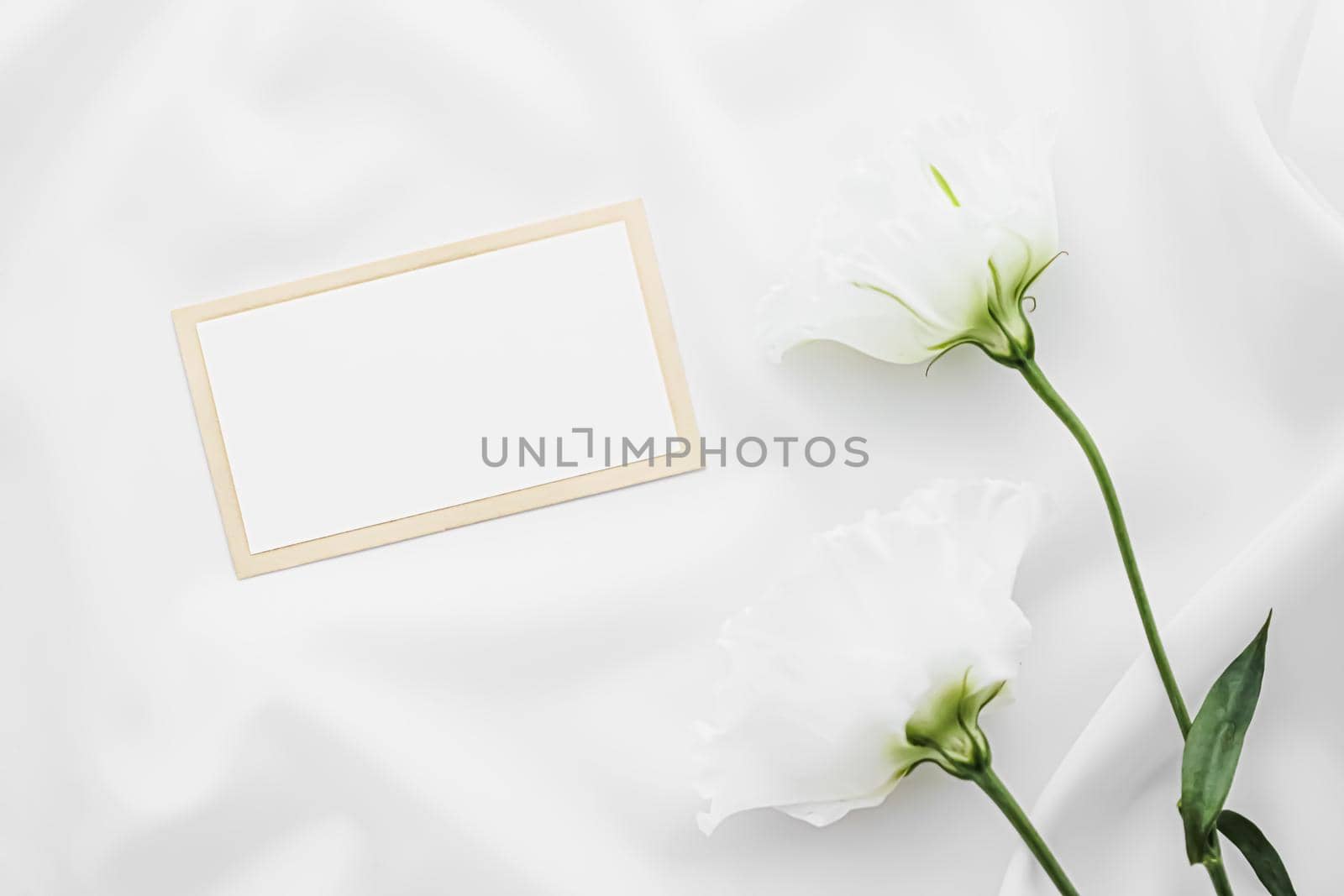 Wedding invitation or gift card and white rose flowers on silk fabric as bridal flatlay background, blank paper and holiday branding, flat lay design by Anneleven