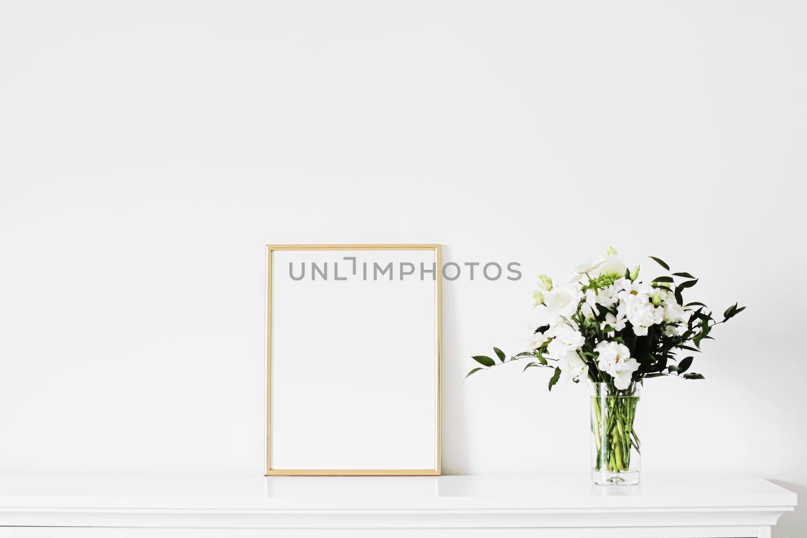 Golden vertical frame and bouquet of fresh flowers on white furniture, luxury home decor and design for mockup creation by Anneleven