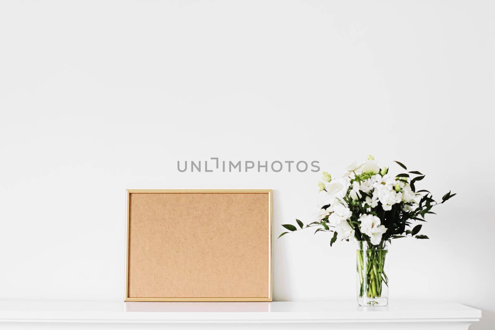 Golden horizontal frame and bouquet of fresh flowers on white furniture, luxury home decor and design for mockup creations