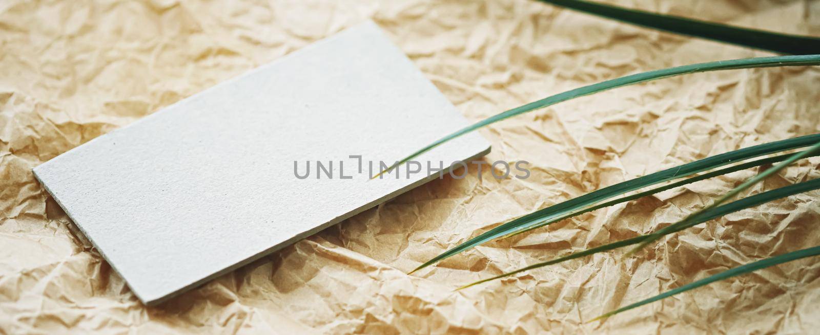 White business card flatlay on brown parchment paper background and green exotic leaf, luxury branding flat lay and brand identity design for mockup by Anneleven