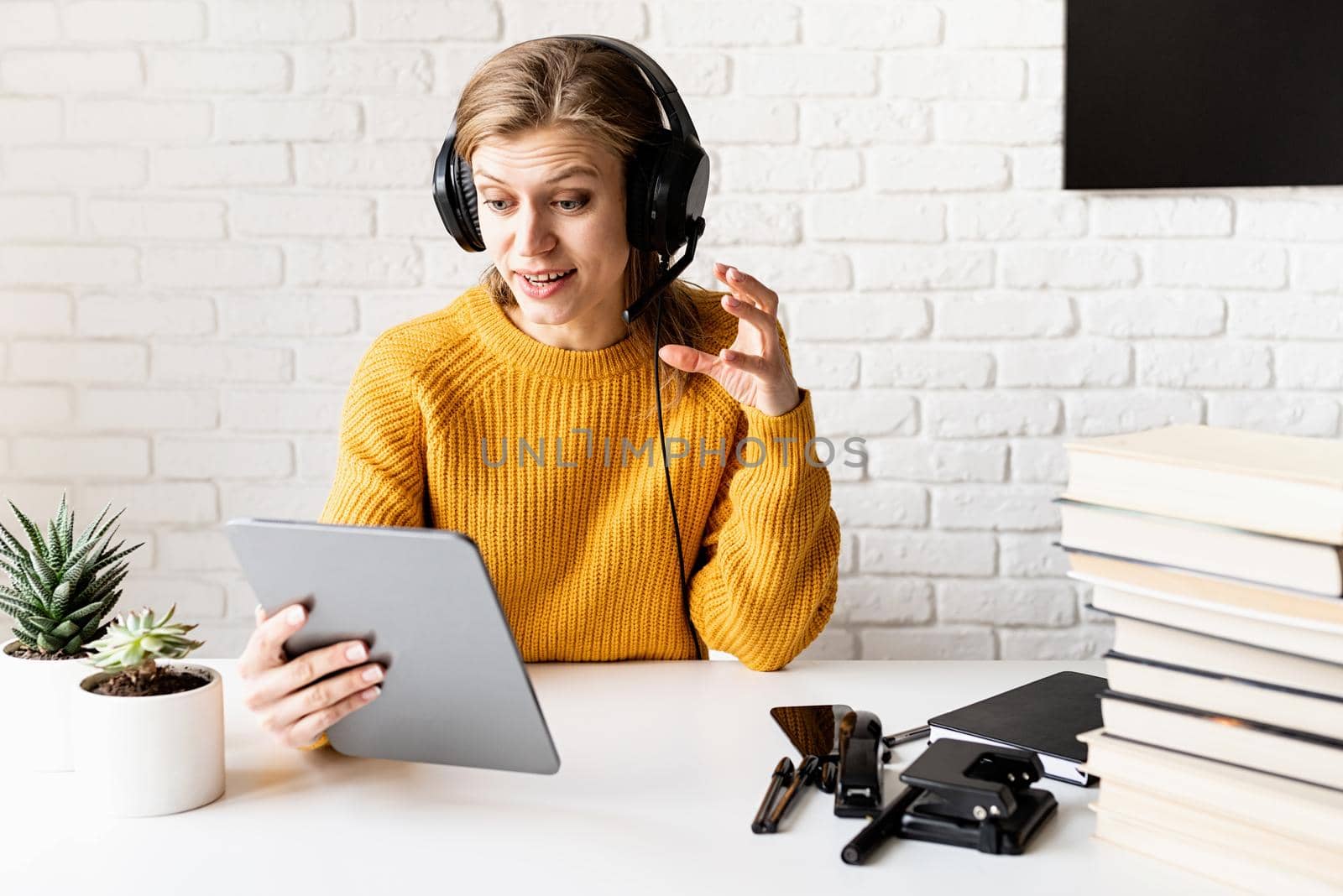 Young smiling woman in black headphones studying online using digital tablet by Desperada