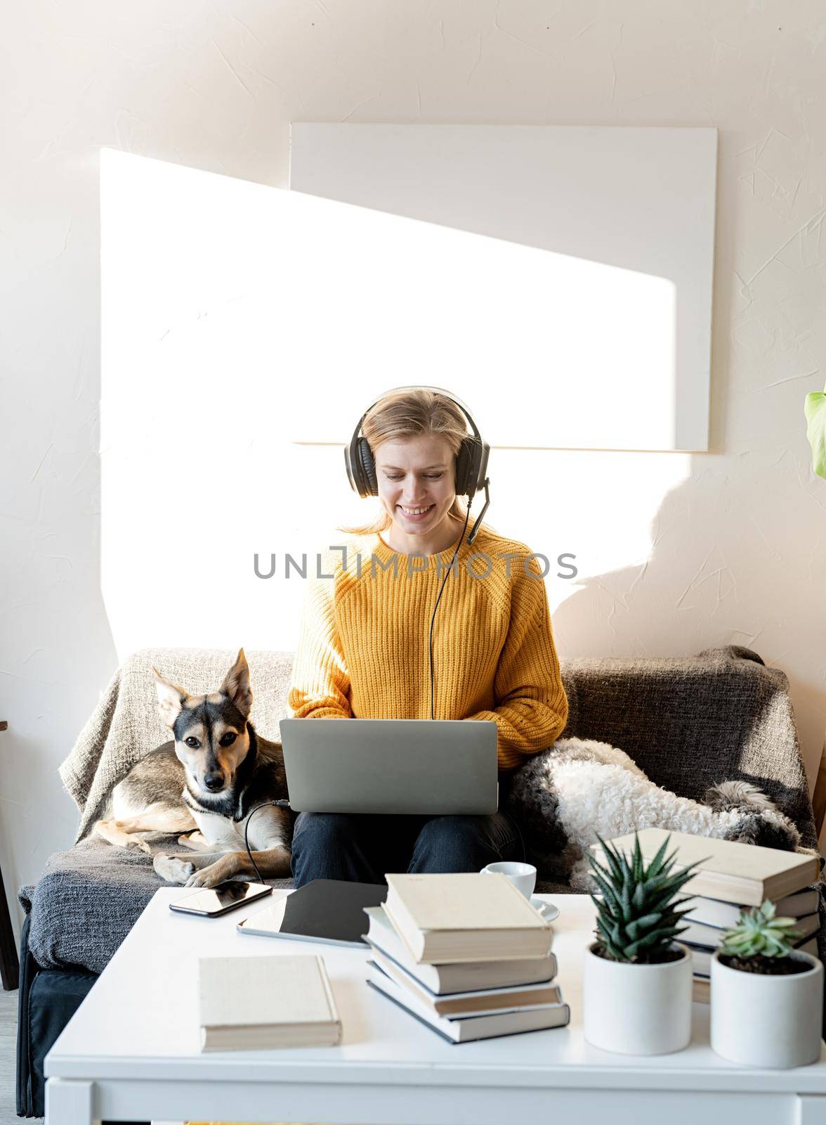 Young smiling woman in black headphones studying online using laptop by Desperada