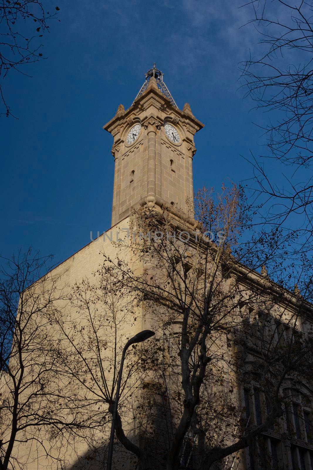 Tower with clock in a historic building in one of the streets of Barcelona in Spain.