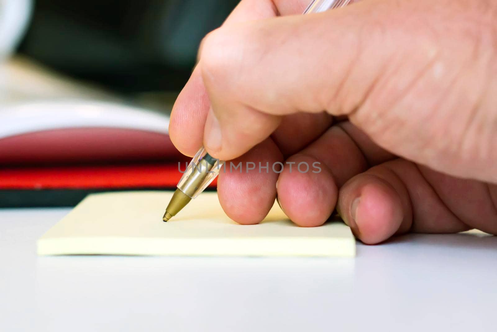 Man writing on a leaflet of paper with a ballpoint pen. by rarrarorro