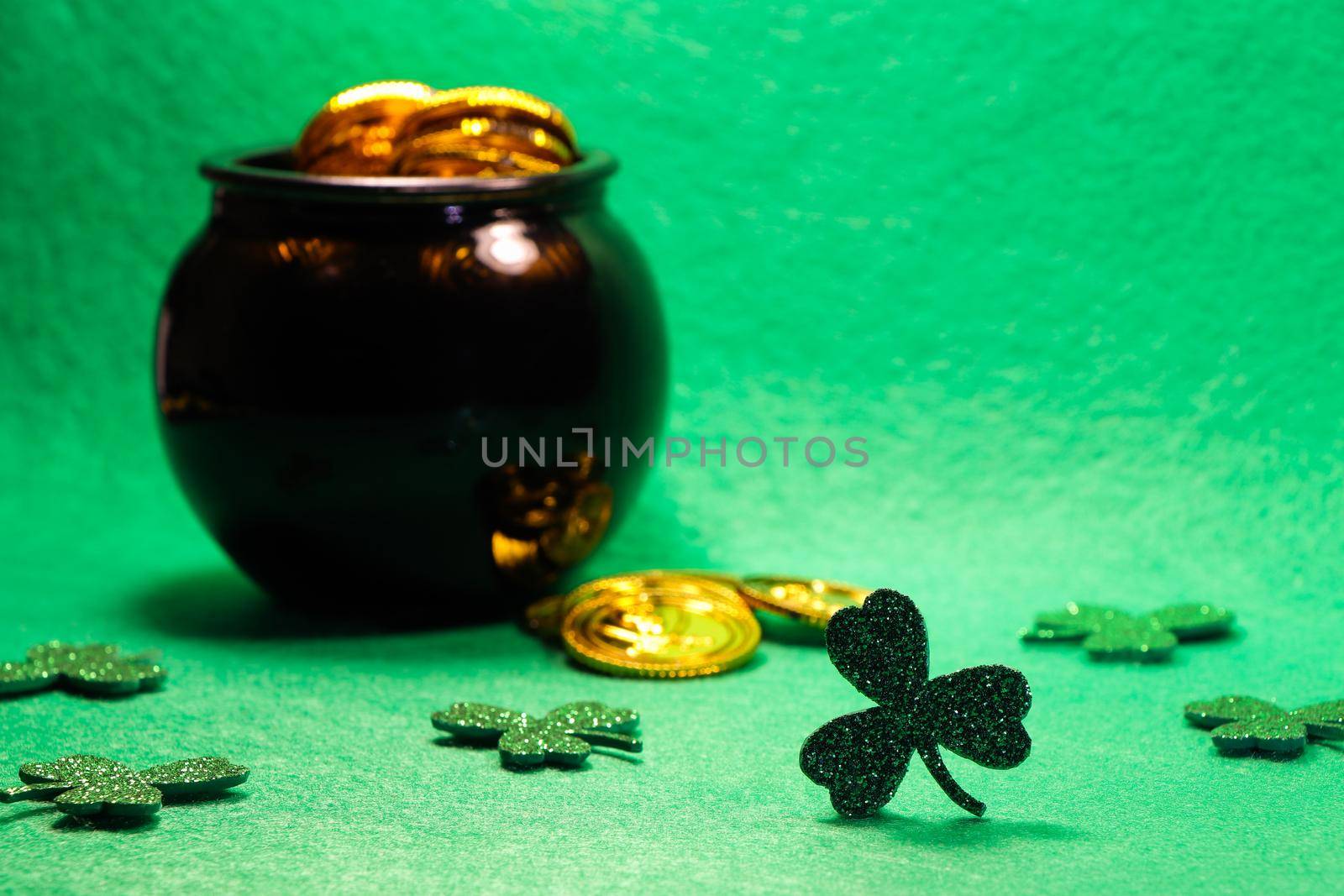 St Patrick's day shamrock clovers with coin filled pot of gold on green