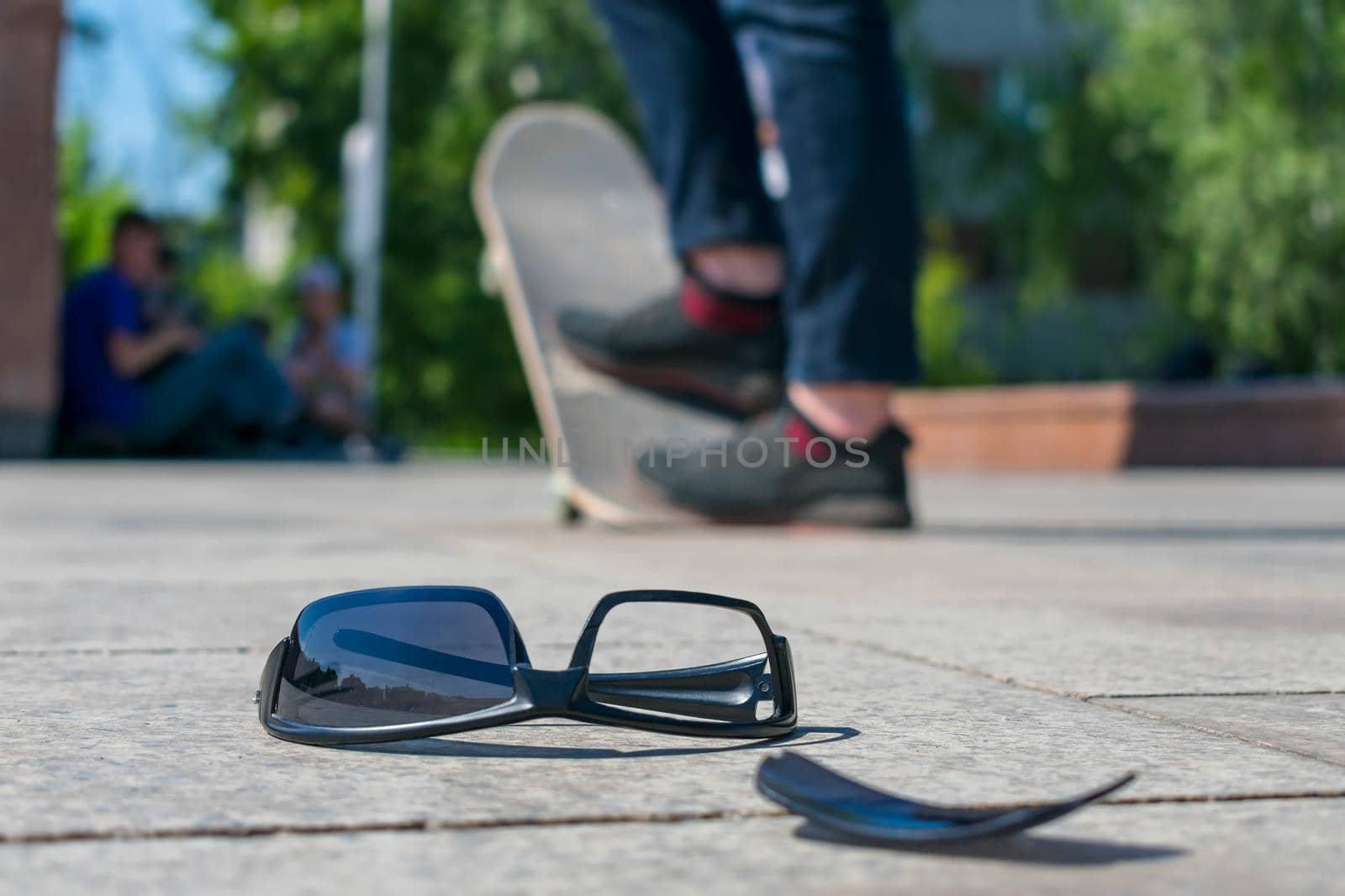 Lost black glasses lie on the road against the background of a man riding a skateboard