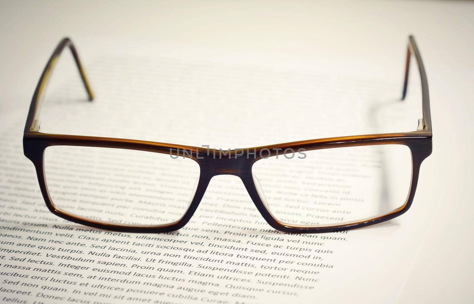 Closeup of eyeglasses on paper sheet with lorem ipsum text. 