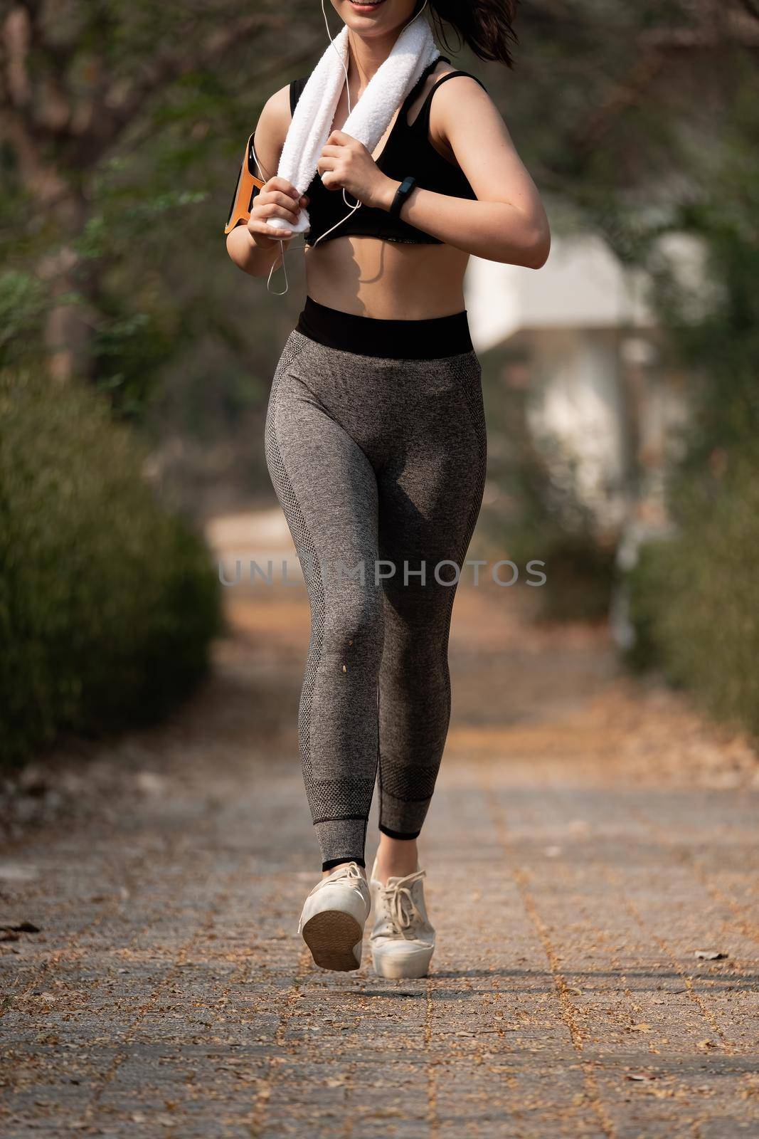 Jogging woman running in park in sunshine on beautiful summer day.