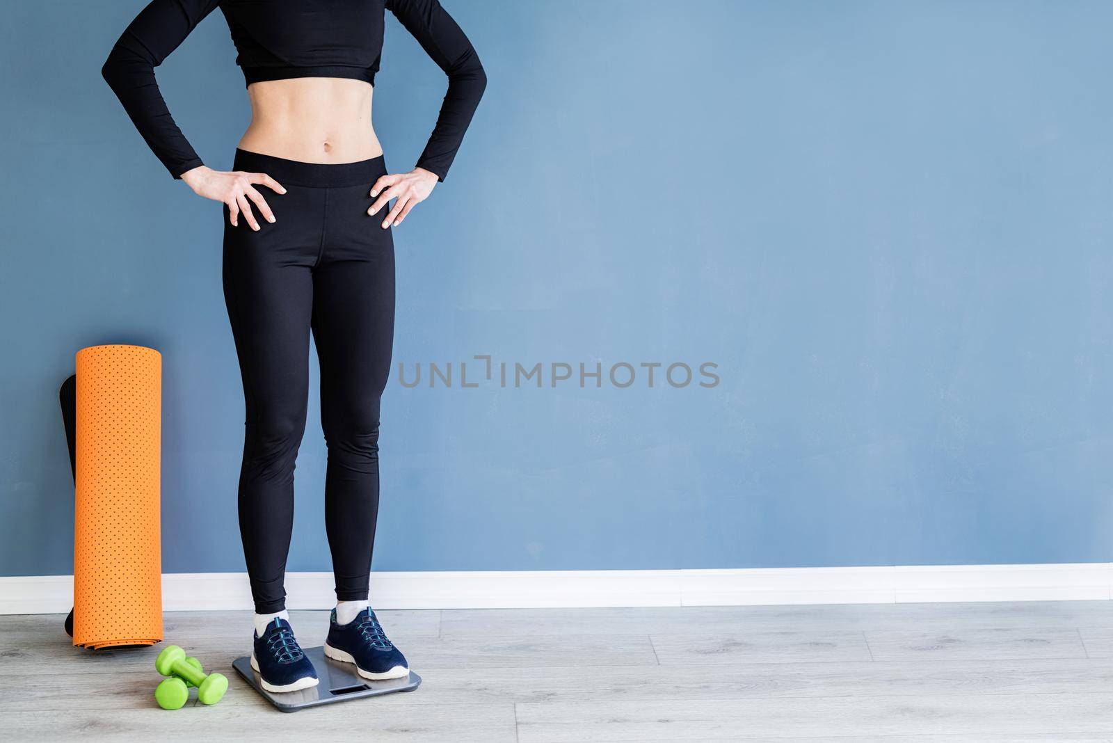 woman in black sport clothes standing on scales by Desperada