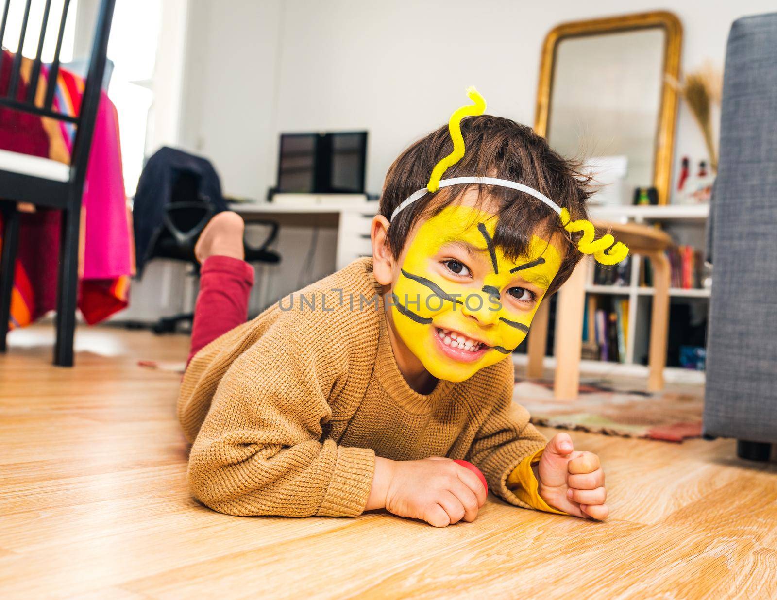 Little boy with bee face paint and playing at home