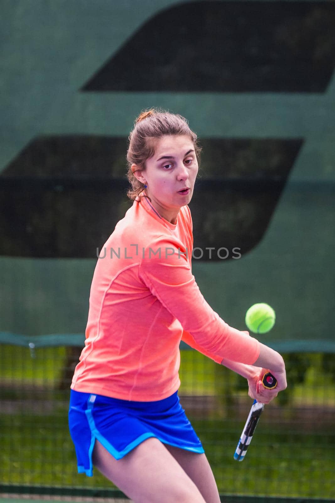 Young woman wearing blue skirt, pink top and tennis shoes during professional tennis match.