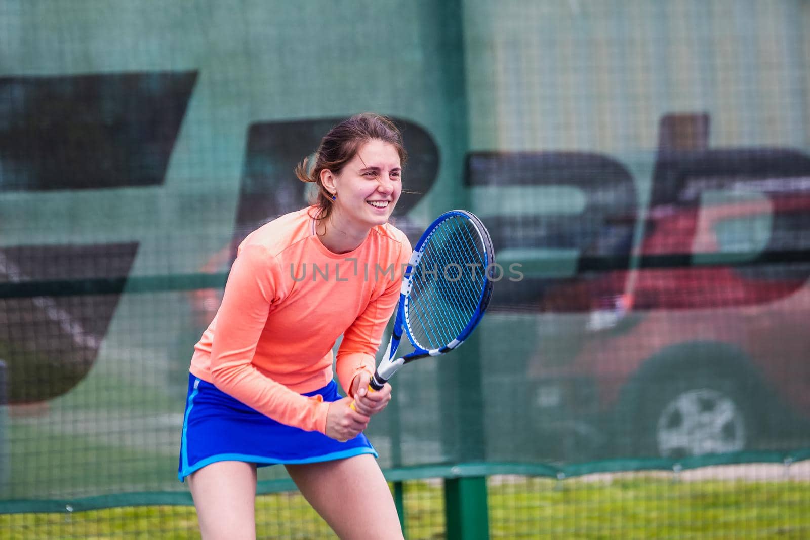Young woman wearing blue skirt, pink top and tennis shoes during professional tennis match.