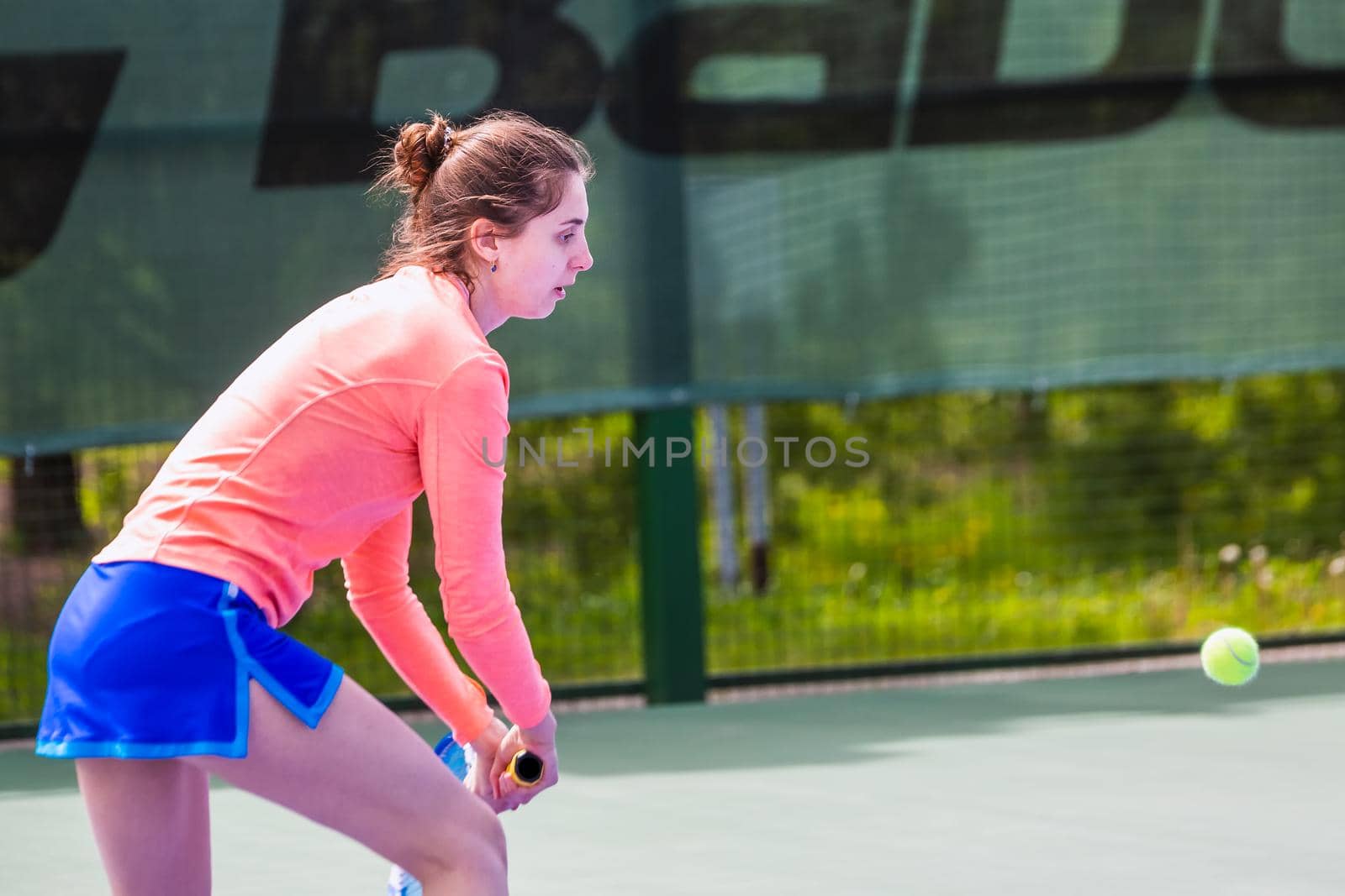Young woman wearing blue skirt, pink top and tennis shoes during professional tennis match.