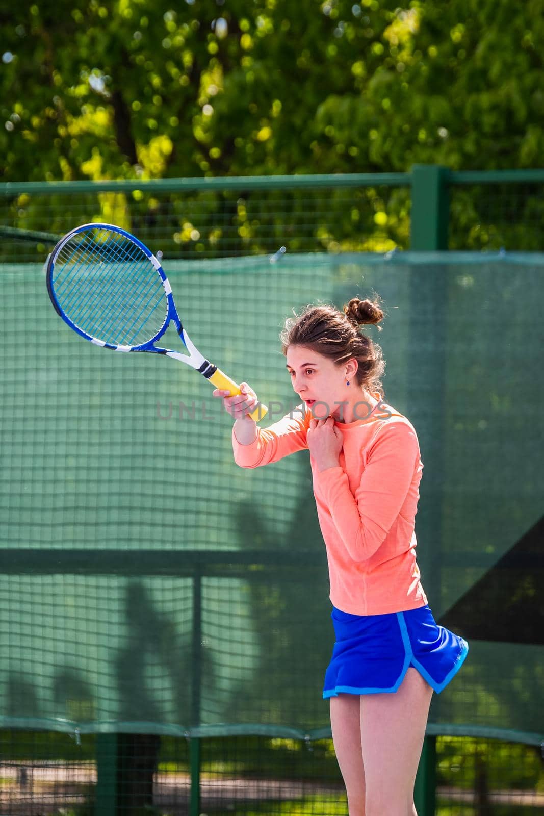 Young woman wearing blue skirt, pink top and tennis shoes during professional tennis match.