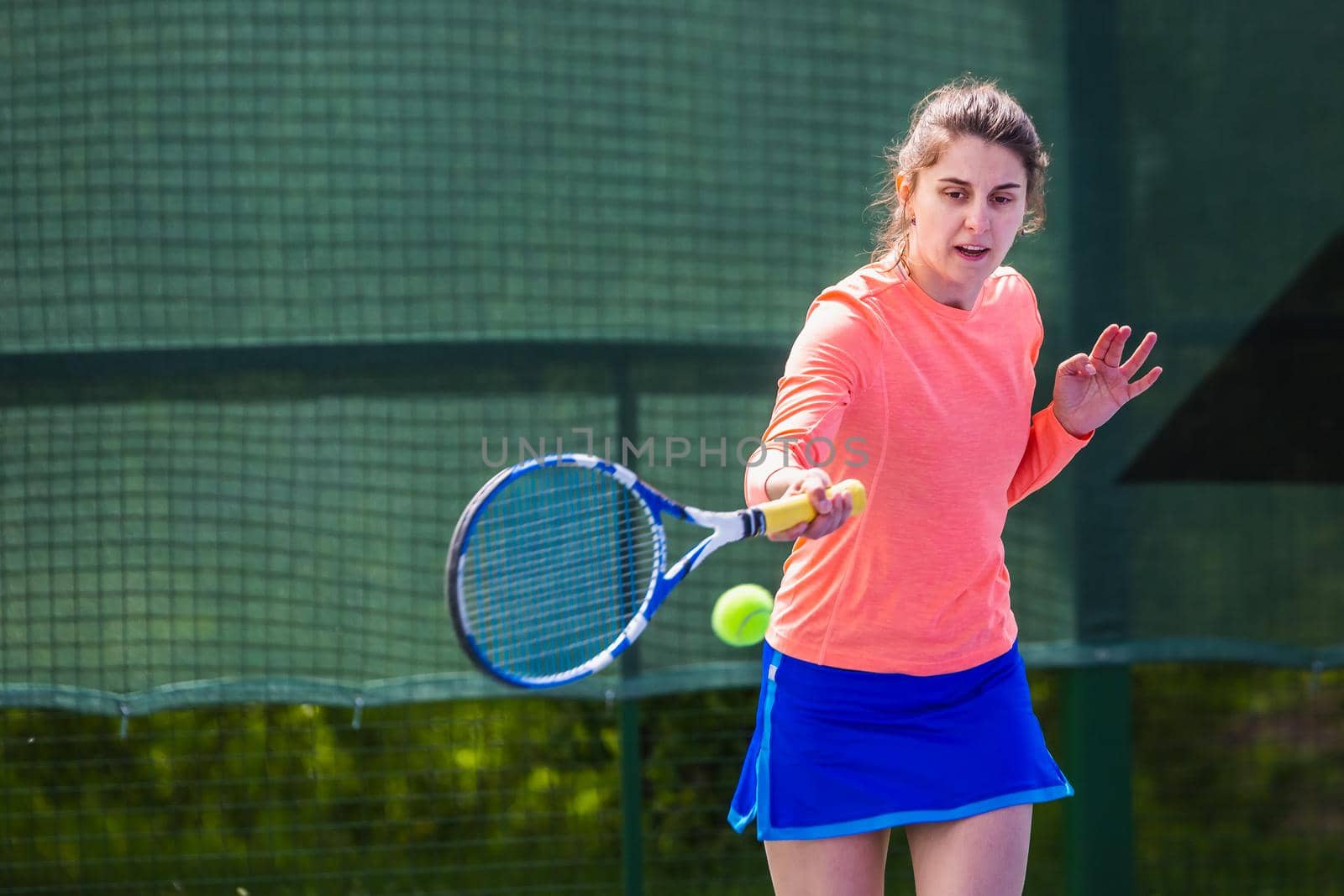 Young woman wearing blue skirt, pink top and tennis shoes during professional tennis match.