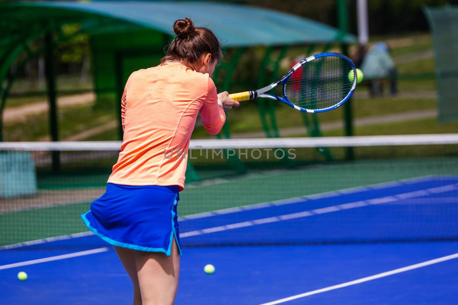 Young woman wearing blue skirt, pink top and tennis shoes during professional tennis match.