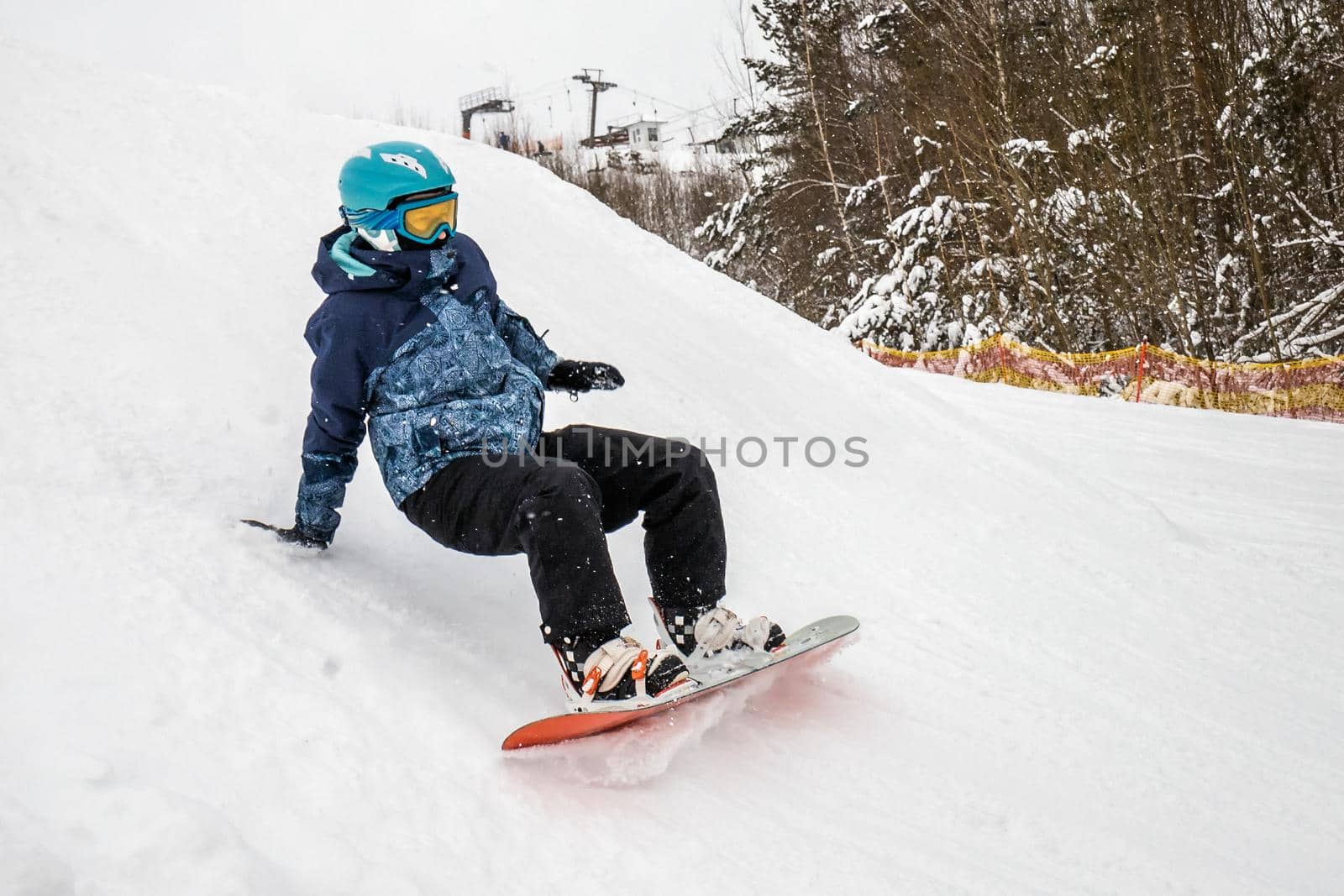 Person go down on a snowboard from the mountainside along a specially prepared track. They make mistakes and fall. Ski vacation. January, Logoisk, Belarus